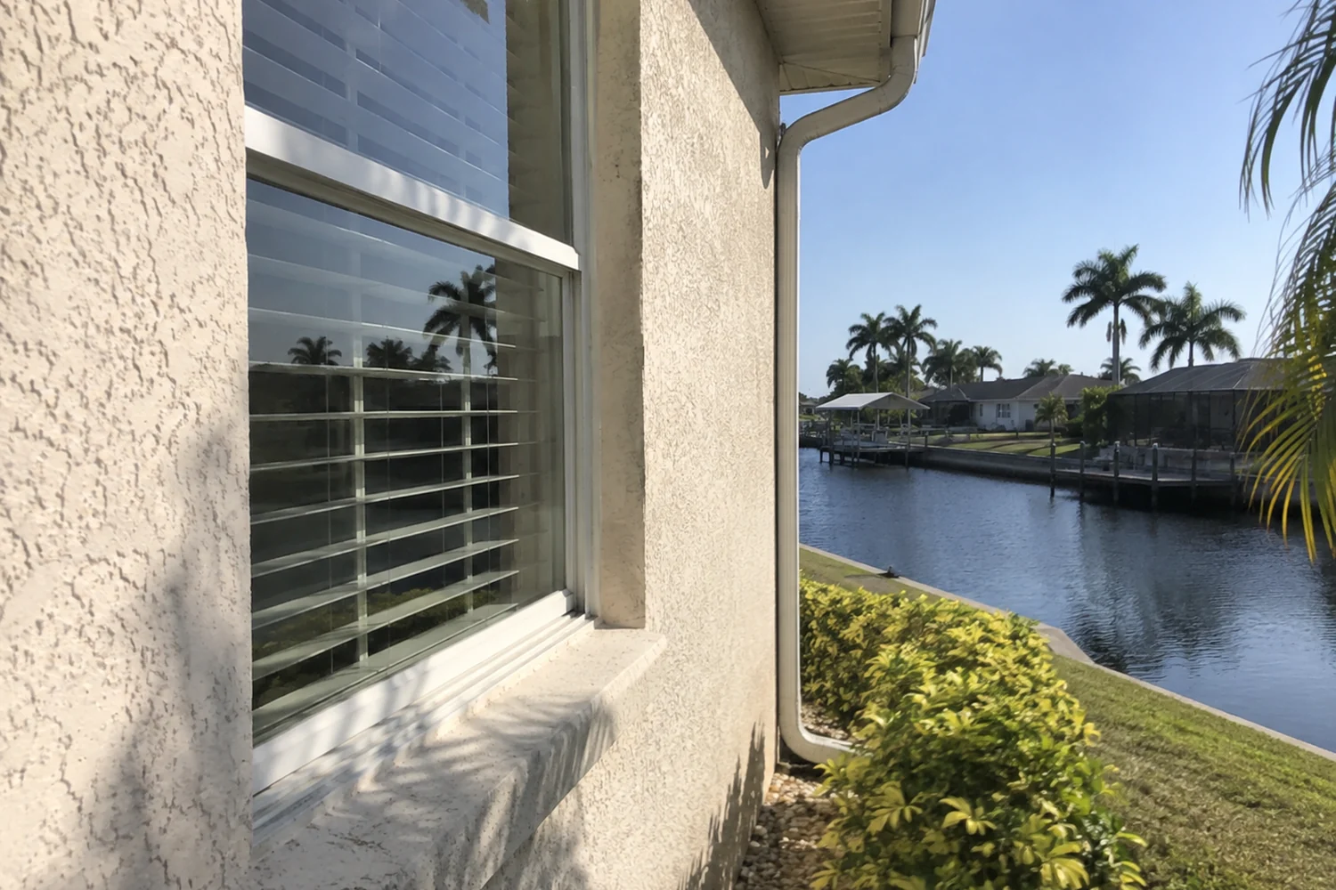 Cape Coral home window and exterior with a small canal-side context in the distance