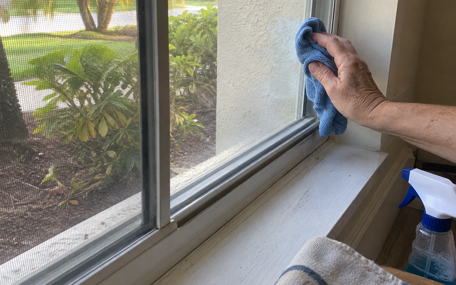 Close view of a residential window being cleaned beside its screen, track, and sill